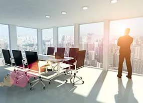 Mann steht in einem Büro und guckt aus dem Fenster
